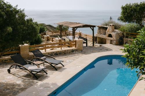 a swimming pool with two chairs and a view of the ocean at Greco Levantes Villas in Triopetra