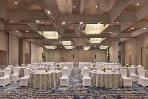 a banquet hall with white tables and white chairs at Navi Mumbai Marriott in Navi Mumbai