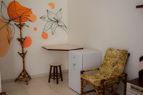 a room with a chair and a refrigerator and a table at Hotel Fazenda Pé da Serra in Bom Sucesso