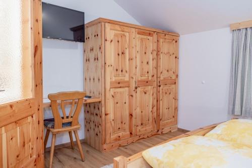 a bedroom with a wooden cabinet and a bed and a desk at Bauernhof Pergila in Maria Luggau