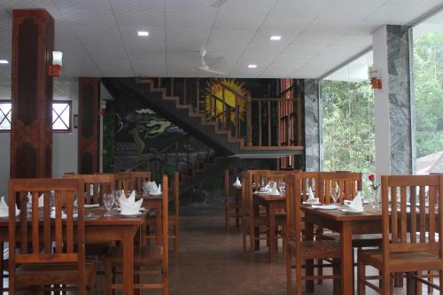 a restaurant with wooden tables and chairs and a staircase at Hotel City Grand Ella in Ella