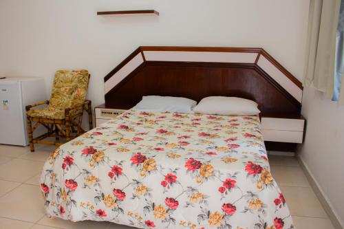 a bedroom with a bed with a floral bedspread at Hotel Fazenda Pé da Serra in Bom Sucesso