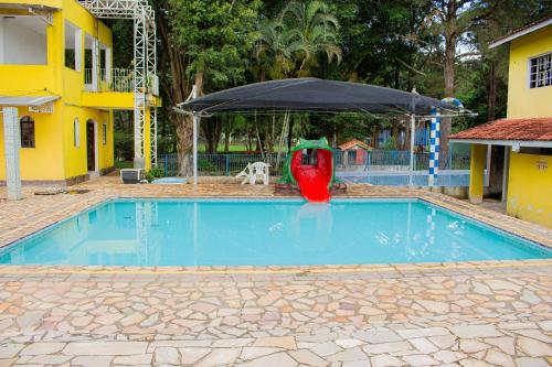 a blue swimming pool with a red object in front of an umbrella at Hotel Fazenda Pé da Serra in Bom Sucesso