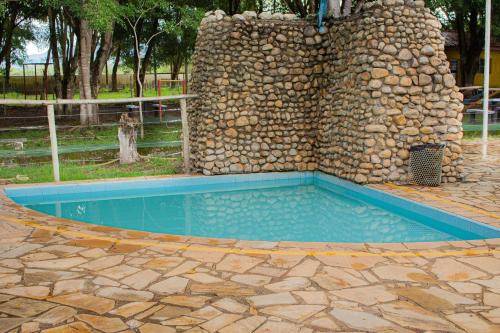a swimming pool in front of a stone wall at Hotel Fazenda Pé da Serra in Bom Sucesso