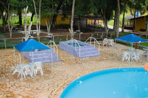 a swimming pool with tables and chairs next to a swimming pool at Hotel Fazenda Pé da Serra in Bom Sucesso