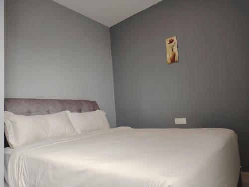 a white bed in a bedroom with a picture on the wall at G9 Hotel Alor Setar in Alor Setar