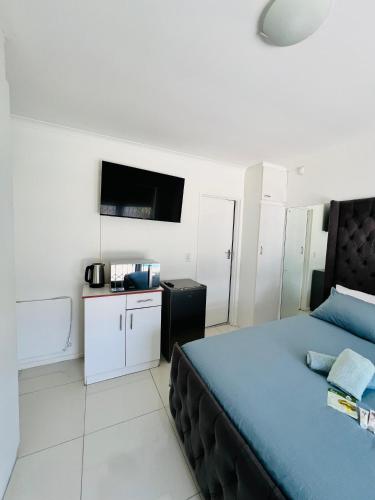 a bedroom with a blue bed and a tv at Private garden guest house in Cape Town