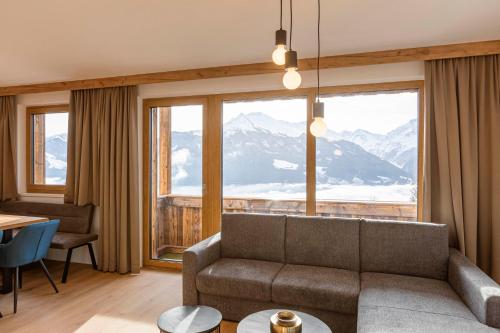 a living room with a couch and a large window at Bergresort Tauernblick by ALPS RESORTS in Mittersill