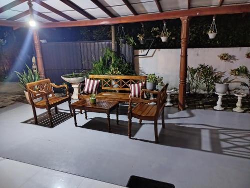 a patio with a wooden bench and two chairs at Little Villa Guest House in Ahangama