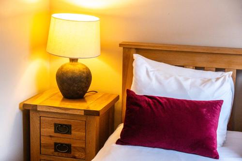 a bed with a red pillow and a lamp on a night stand at The Jewellery Suites Birmingham in Birmingham