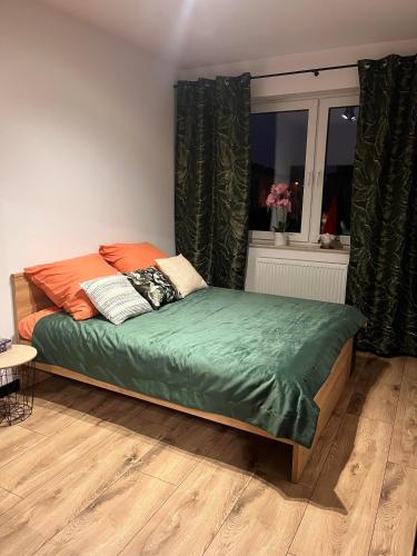a bedroom with a bed with green sheets and a window at Apartament Juleczka in Biała Podlaska