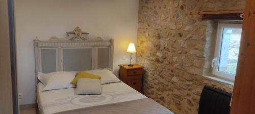 a bedroom with a bed with a stone wall at Gîte de Lou Mas in Savasse