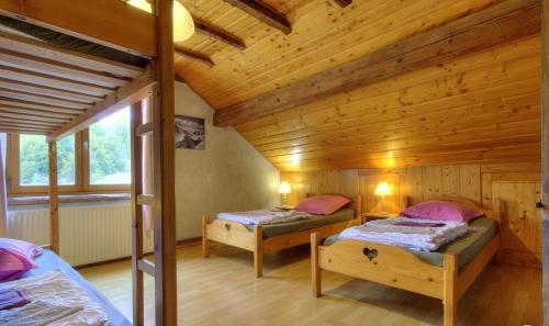 a bedroom with two beds in a wooden cabin at La Grange des Plans in Le Grand-Abergement