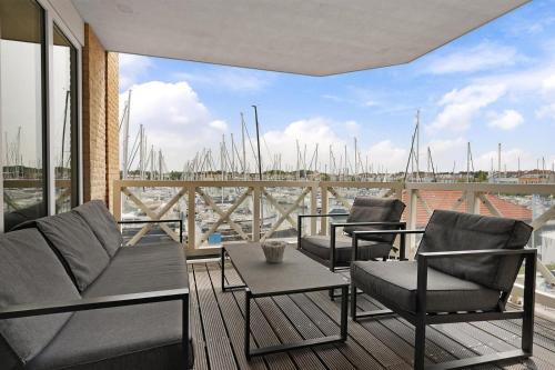 a balcony with chairs and tables and a view of a marina at Kabbelaarsbank 411 - Port Marina Zélande NOT INTENDED FOR COMPANY OR WORK-RELATED STAYS in Ouddorp