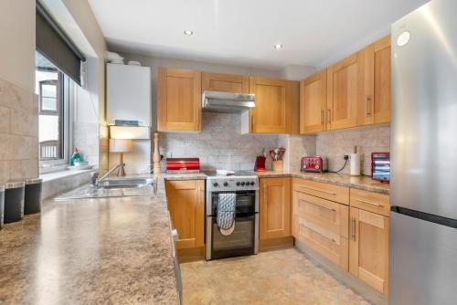 a kitchen with wooden cabinets and stainless steel appliances at The Jewellery Suites Birmingham in Birmingham