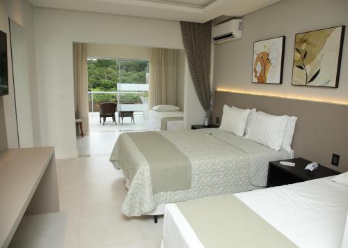 a hotel room with two beds and a balcony at Resort Ecoar in Gaspar