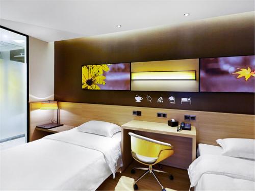 a bedroom with two beds and a desk and a chair at 7Days Inn Premium Beijing Chaoyangmen in Beijing