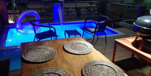 a table and chairs in front of a swimming pool at Chalé Pé na Areia e Piscina Privativa em Barra do Jacuípe in Camaçari
