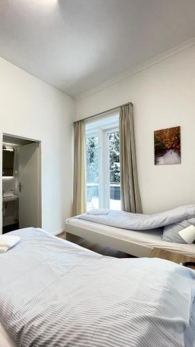 two beds in a room with a window at Villa Zentrum Haus Davos in Davos