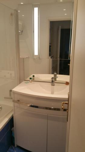 une salle de bain avec un lavabo blanc et un miroir dans l'établissement Moderne Appartement Cannes Californie, à Cannes