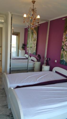 une chambre avec deux lits avec des murs violets et un miroir dans l'établissement Moderne Appartement Cannes Californie, à Cannes