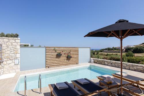 a swimming pool with an umbrella and some tables and chairs at Eveland Accessible Villas in Sfakaki