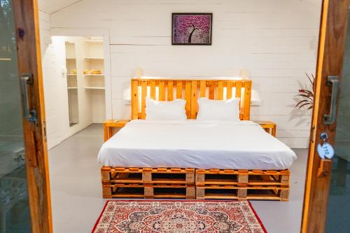 a bedroom with a wooden bed with white sheets at The Pearl Beach Resort in Canacona