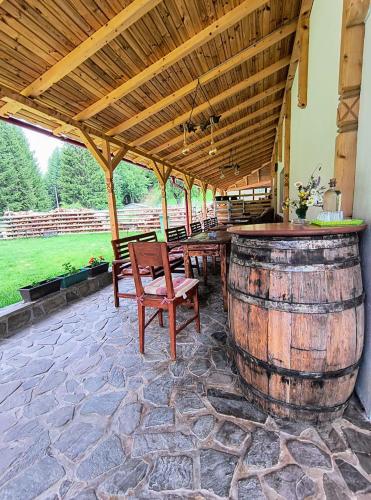 a patio with a table and chairs and a wine barrel at Poiana Sașilor - Valea Doftanei in Trăisteni