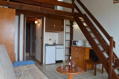 Cette chambre dispose d'une cuisine avec un escalier et une table. dans l'établissement SP080-016 Studio cabine mezzanine 5 couchages SAINT PIERRE LA MER, à Saint Pierre La Mer