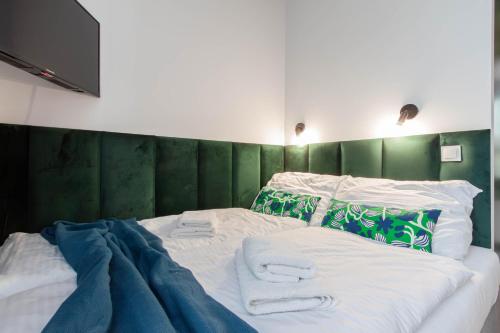 a bed with a green headboard and towels on it at Apartamenty Silver Place in Szczecin