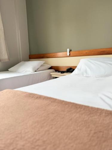 two beds in a hotel room with white sheets at Fenicia Palace Hotel in Varginha
