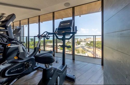 ein Fitnessraum mit einem Fahrrad in einem Zimmer mit Fenstern in der Unterkunft beira-mar pajuçara in Maceió