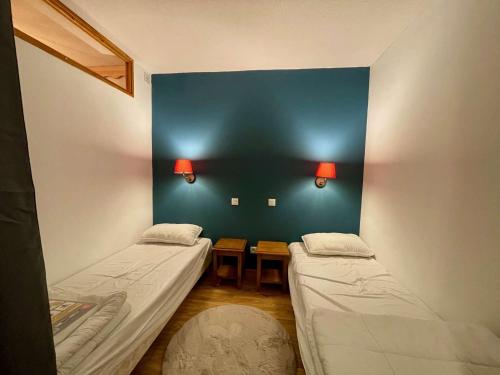 Cette chambre comprend 2 lits et un mur bleu. dans l'établissement Charmant 2 pièces 6 pers, piscine chauffée, sauna, ski aux pieds - Les Orres 1800 - FR-1-322-636, aux Orres