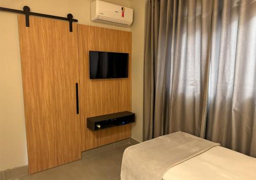 a bedroom with a bed and a cabinet with a tv at Fenicia Palace Hotel in Varginha