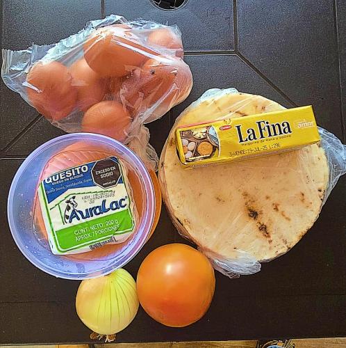 een tafel met eieren, tomaten, uien en een zak kaas bij Cabaña Madre Selva in San Vicente