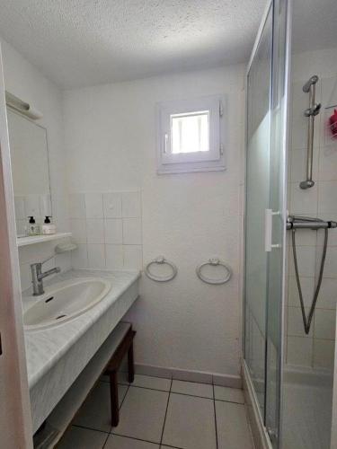 une salle de bain blanche avec un lavabo et une douche dans l'établissement PERLES DU SOLEIL Jolie villa T2 mezzanine piscine Rochelongue Cap d'Agde, au Cap d'Agde