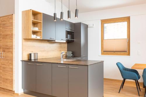 a kitchen with gray cabinets and a blue chair at Bergresort Tauernblick by ALPS RESORTS in Mittersill