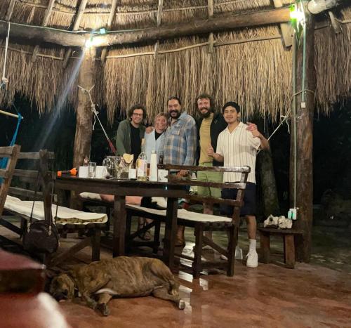 a group of people standing around a table with a dog at Space for your tent in Tulum