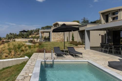 a swimming pool with chairs and a house at Fari Stone Villas in Skala Marion