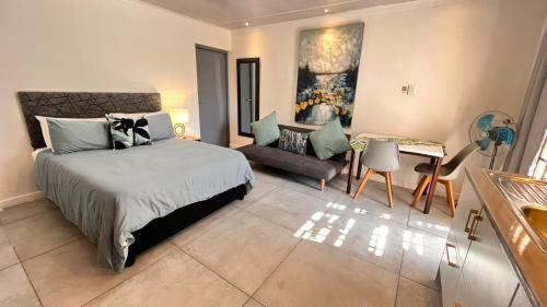 a bedroom with a bed and a table and a couch at Lagoon Lodge in Cape Town