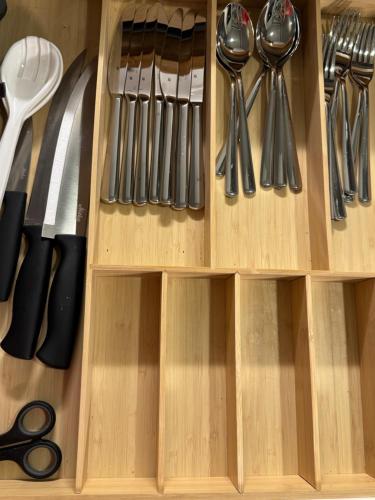 a wooden drawer with knives and utensils at Your Chic Vibrant APT in Helsinki
