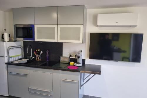 une cuisine avec des armoires blanches et un comptoir noir dans l'établissement Naturiste Cap d'Agde Port Vénus 7, au Cap d'Agde