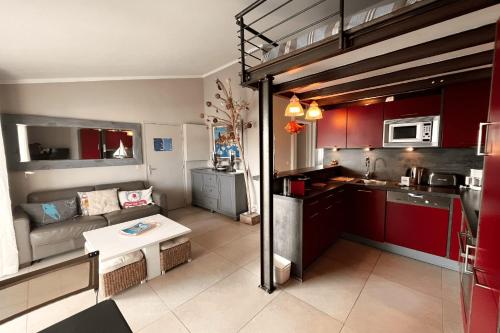 Il comprend une petite cuisine et un salon avec des placards rouges. dans l'établissement Renovated 3-room apartment with WIFI and a large balcony, à Grimaud