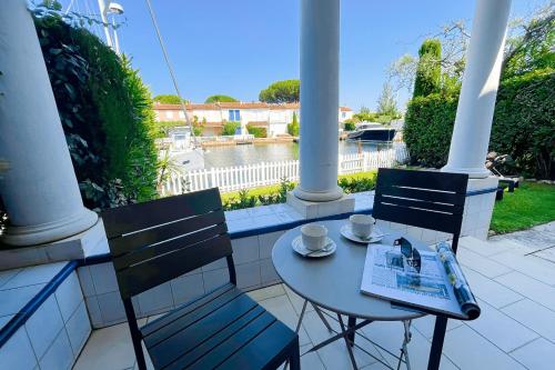 - une table et des chaises sur une terrasse couverte offrant une vue sur l'eau dans l'établissement Wide house with WIFI and AC a terrace a garden and a 12m mooring, à Grimaud