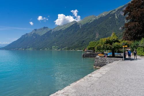 people walking along the shore of a lake with mountains at Charming Apartment-Prime Location in Brienz