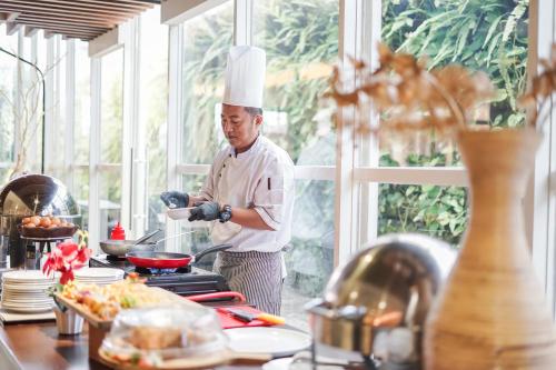 a chef standing in a kitchen preparing food at Satoria Hotel Yogyakarta - CHSE Certified in Yogyakarta