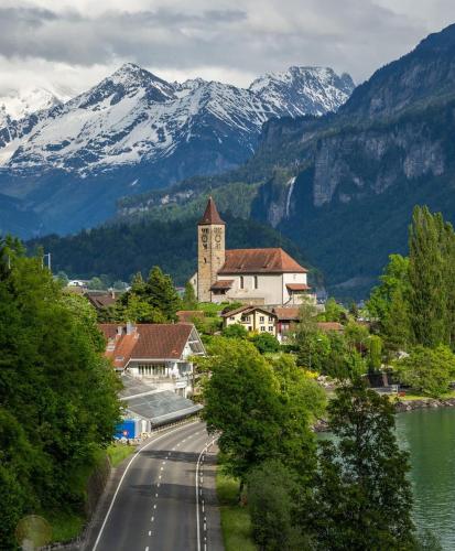 a road in a town with a clock tower and mountains at Charming Apartment-Prime Location in Brienz