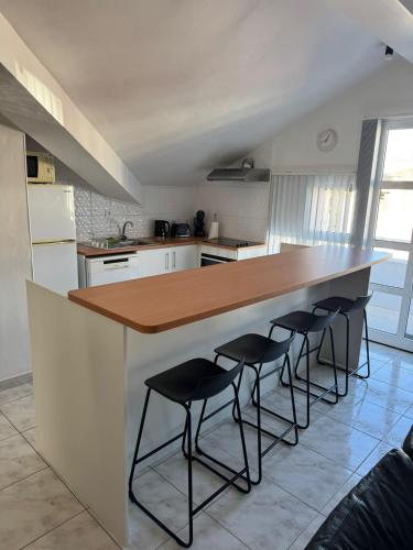 a kitchen with a counter with four bar stools at Oásis da Praia in Praia da Vitória