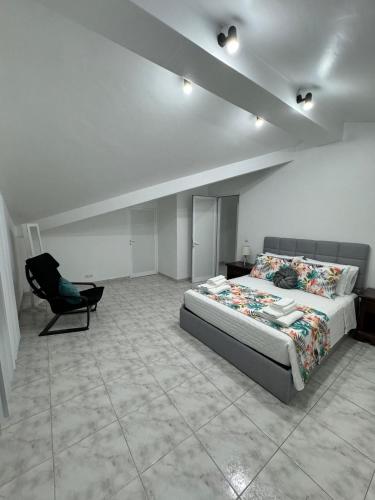 a bedroom with a bed and a chair in it at Oásis da Praia in Praia da Vitória