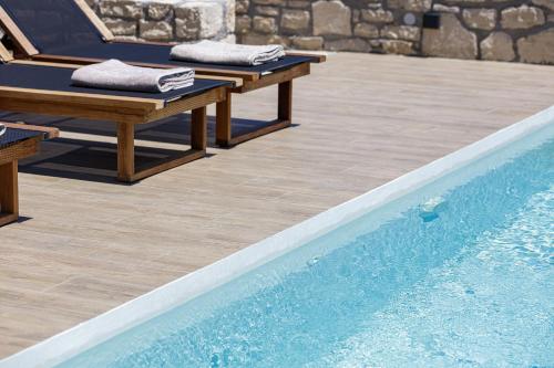 two benches sitting next to a swimming pool at Eveland Accessible Villas in Sfakaki